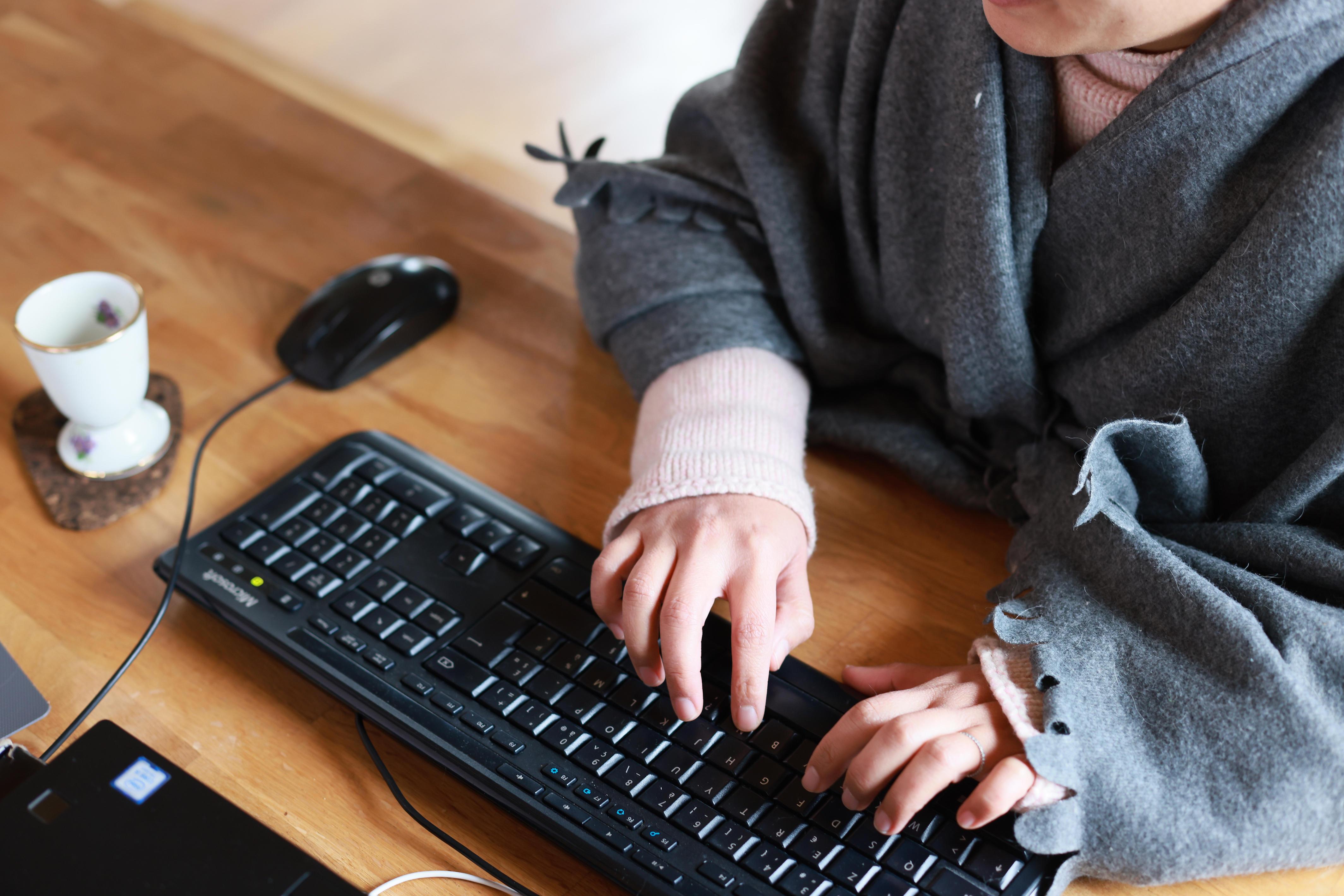 Frau mit Decke am Computer. 
