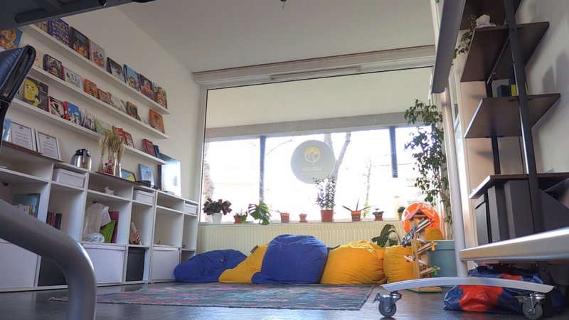 Ein Raum mit Bücherregalen an der Wand und gelben und blauen Sicksäcken.