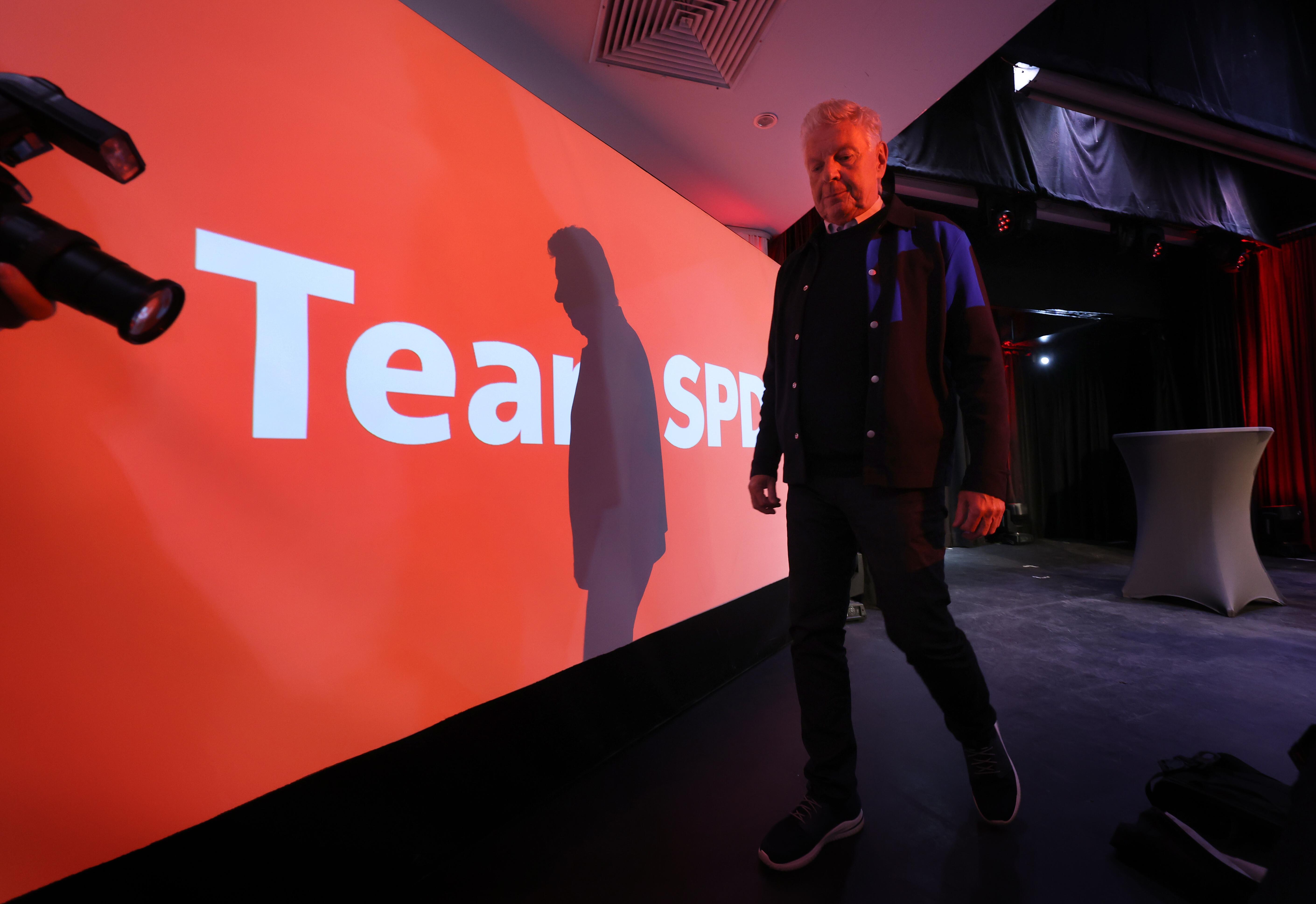 Dieter Reiter in rotem Licht neben einer roten Wand mit SPD-Schriftzug; Reiter wirft einen Schatten auf die Wand