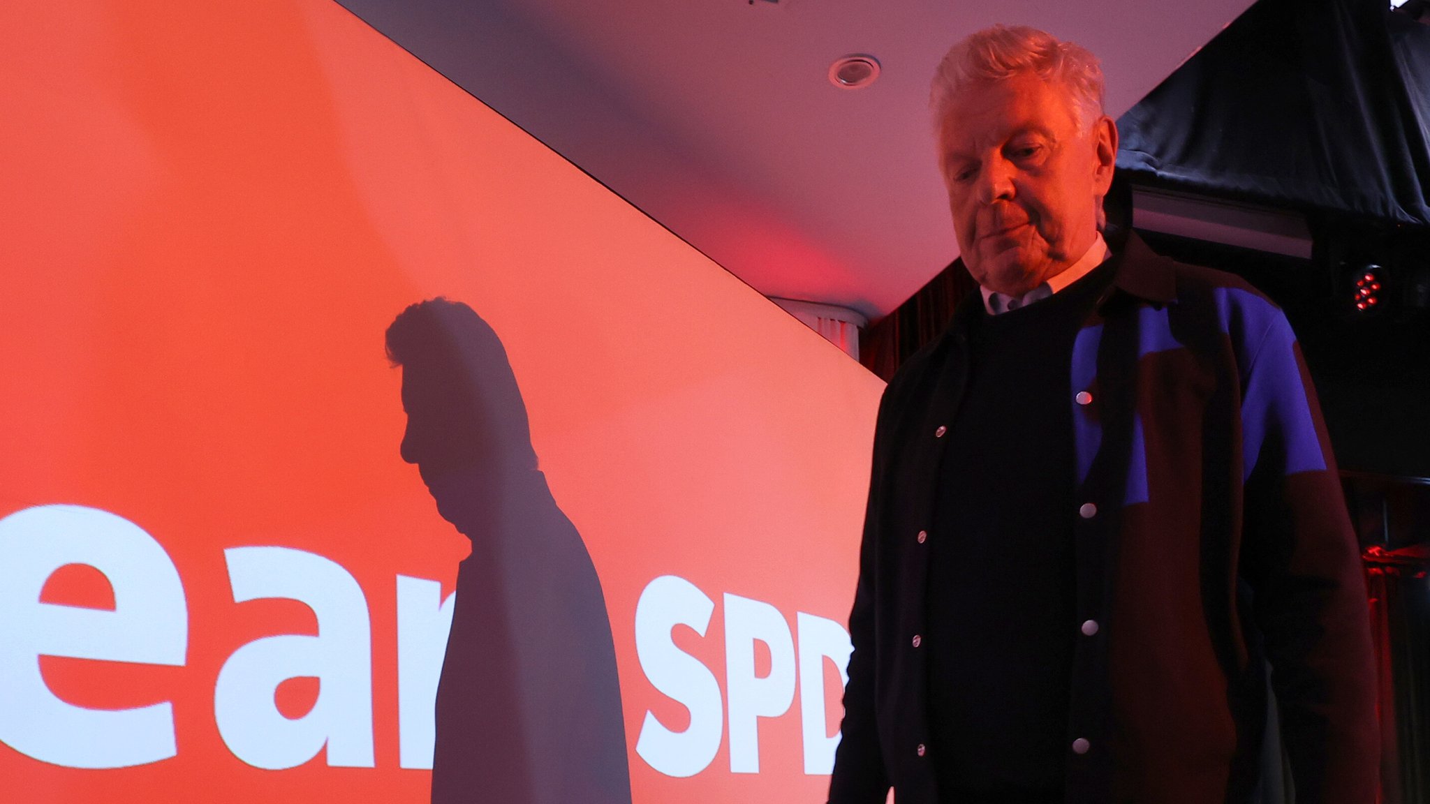 Dieter Reiter in rotem Licht neben einer roten Wand mit SPD-Schriftzug; Reiter wirft einen Schatten auf die Wand