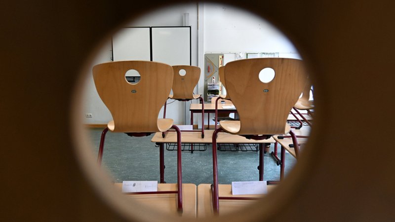 Blick durch ein Türloch in ein Klassenzimmer, in dem die Stühle auf den Bänken stehen. | Bild: dpa-Bildfunk/Arne Dedert Blick durch ein Türloch in ein Klassenzimmer, in dem die Stühle auf den Bänken stehen.