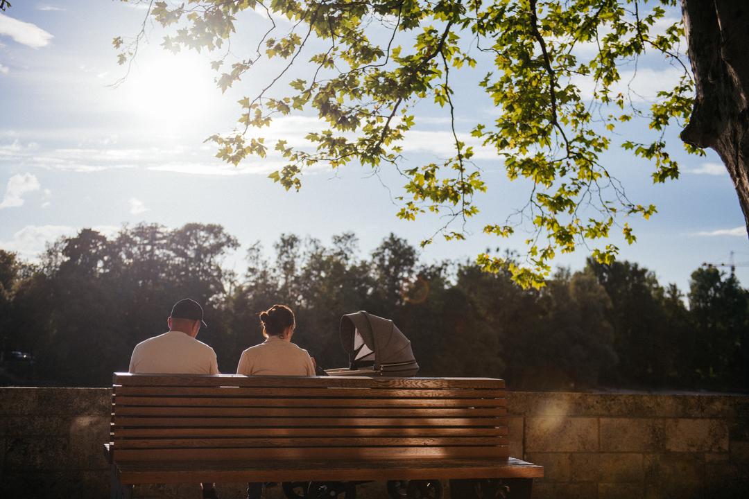 Ein Paar mit Kinderwagen sitzt in der Abendsonne.