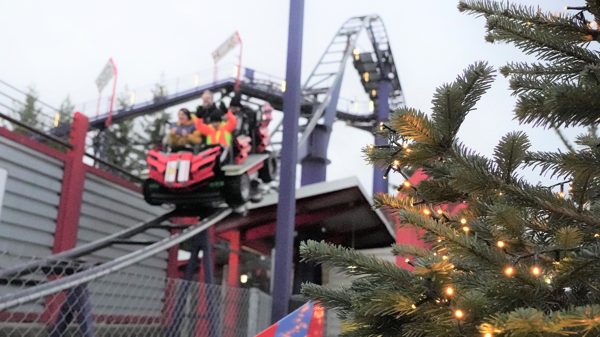 Achterbahn im Winter mit Weihnachtsbaum im Vordergrund