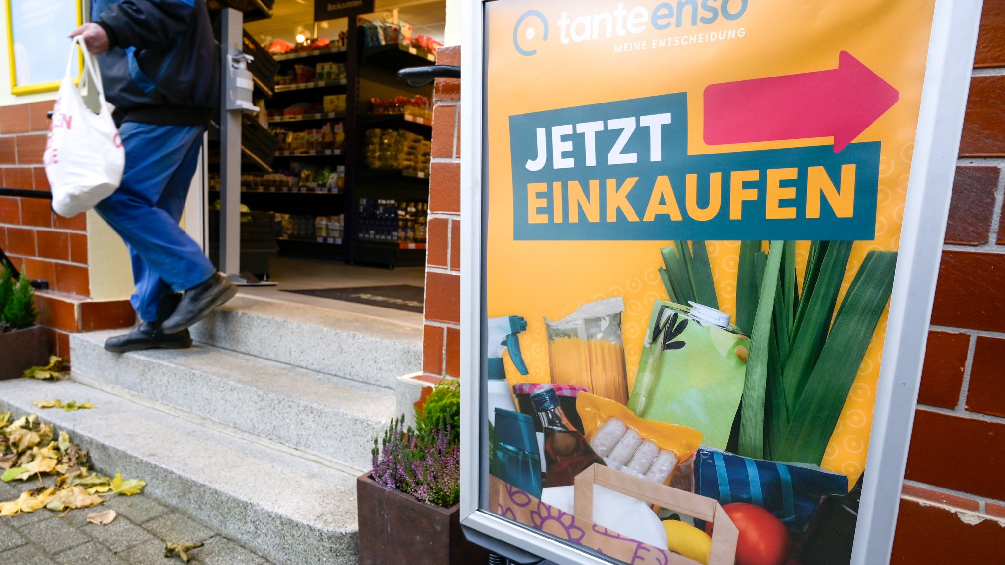 Ein Aufsteller mit der Aufschrift "Jetzt einkaufen" steht vor einem Tante-Enso-Laden.