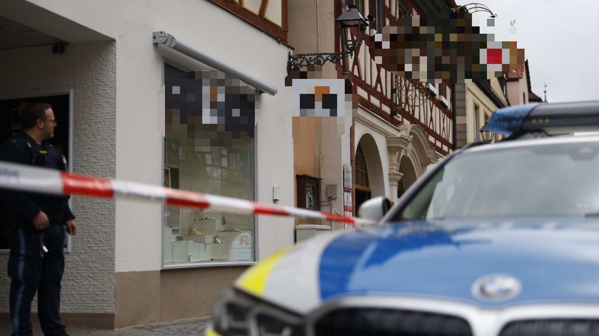 Ein Polizeiauto und ein Absperrband vor einer Hauswand.