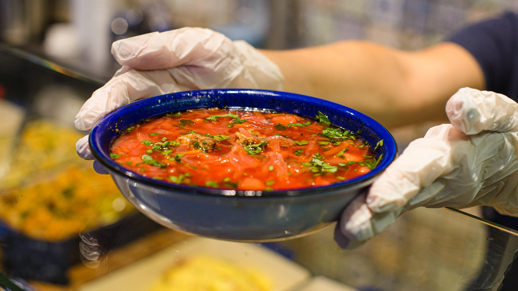 Teller mit Suppe wird über den Kantinentresen gereicht 