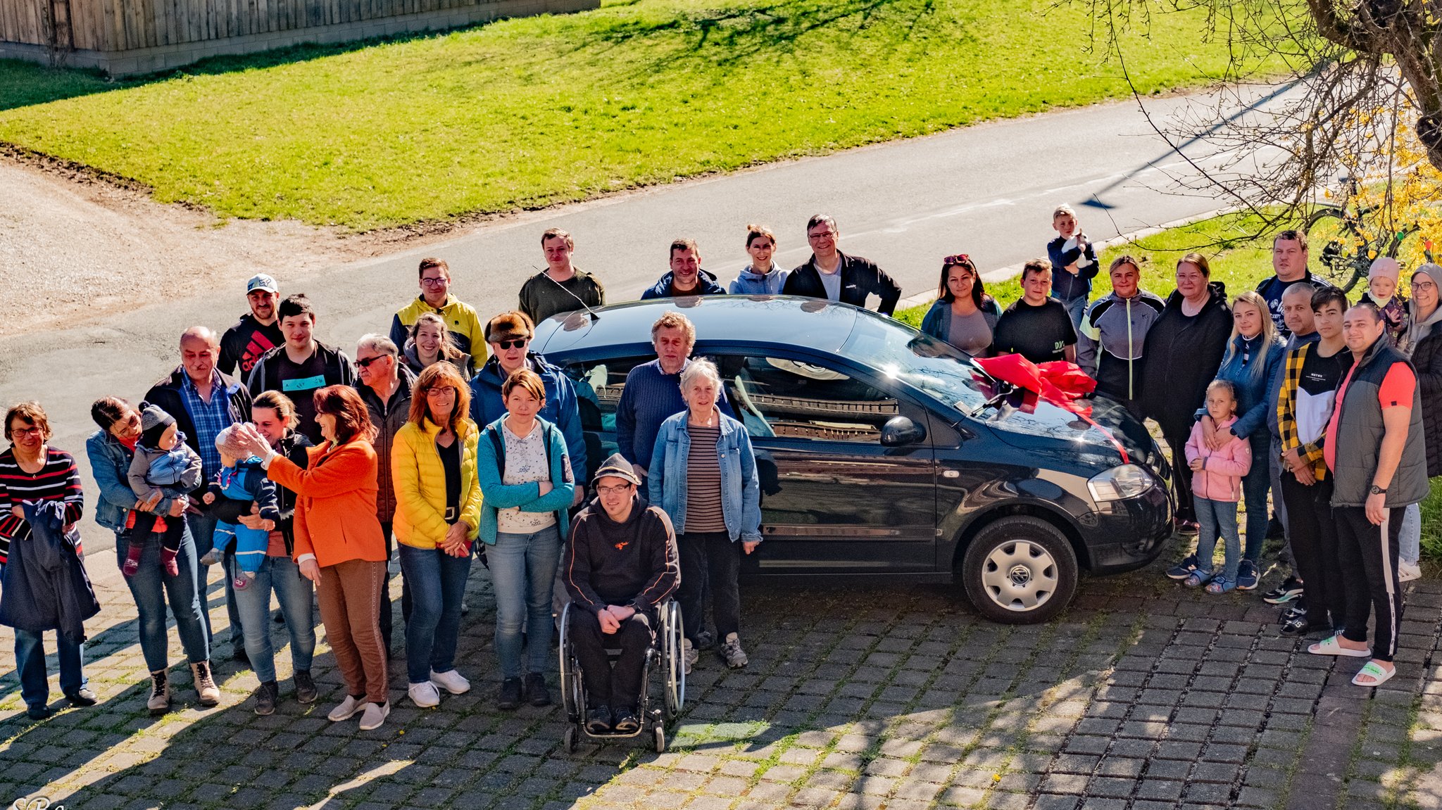 Menschen stehen in Saugendorf um ein schwarzes Auto herum.