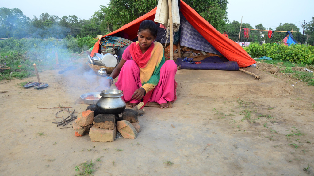 Ein junges Mädchen kocht vor ihrer einfachen Unterkunft im indischen Allahabad. 