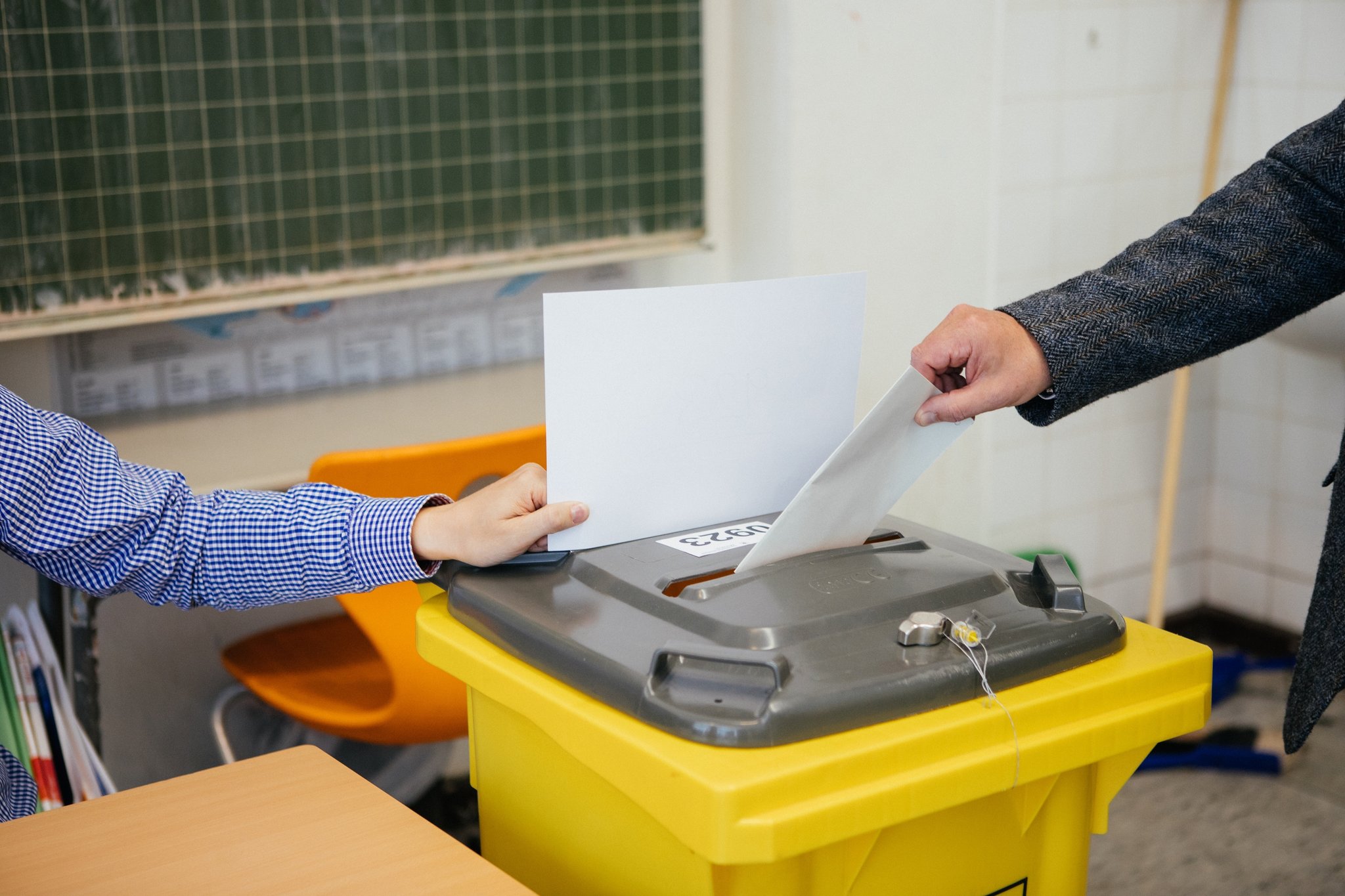Ein Stimmzettel wird in die Wahlurne geworfen.