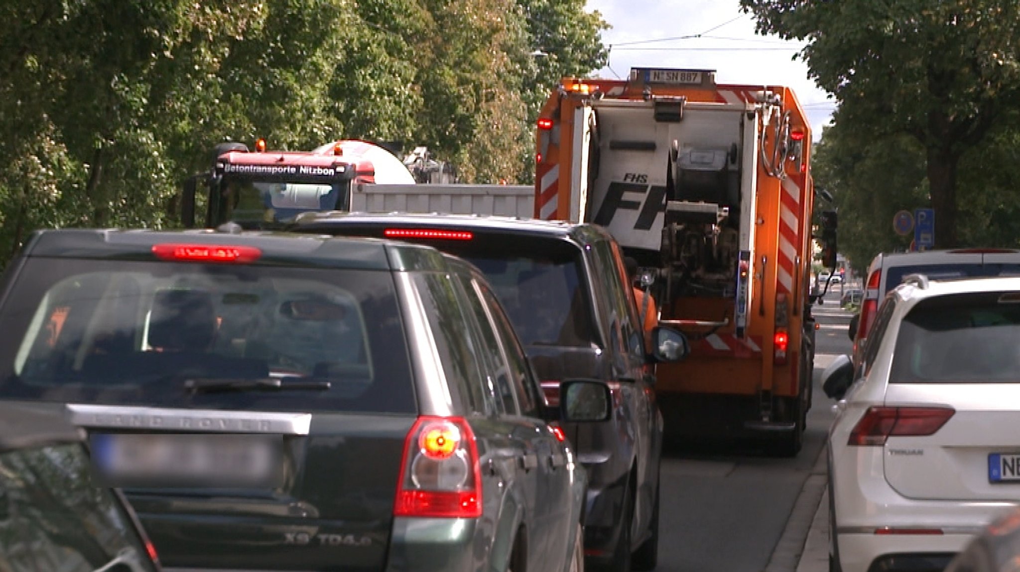 Ein Müllfahrzeug steht in einer Baustelle, um Tonnen zu lernen. Die Autos dahinter müssen warten | Bild: BR Ein Müllfahrzeug steht in einer Baustelle, um Tonnen zu lernen. Die Autos dahinter müssen warten