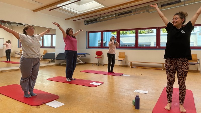 Vier Frauen praktizieren in einer Turnhalle Yoga. | Bild: BR / Julia Demel Vier Frauen praktizieren in einer Turnhalle Yoga.