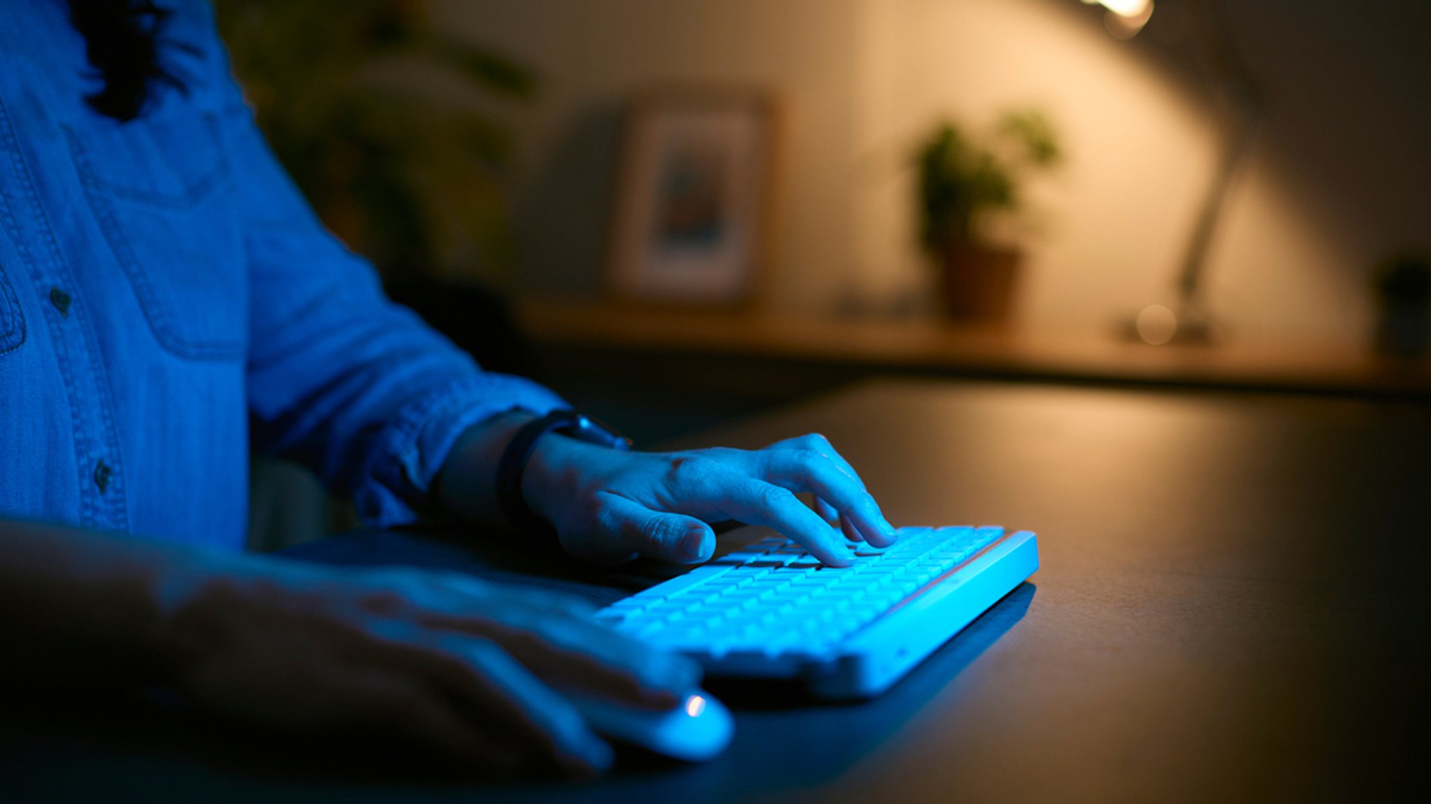 Eine Frau sitzt abends vor dem Computer an ihrem Schreibtisch. (Symbolbild)