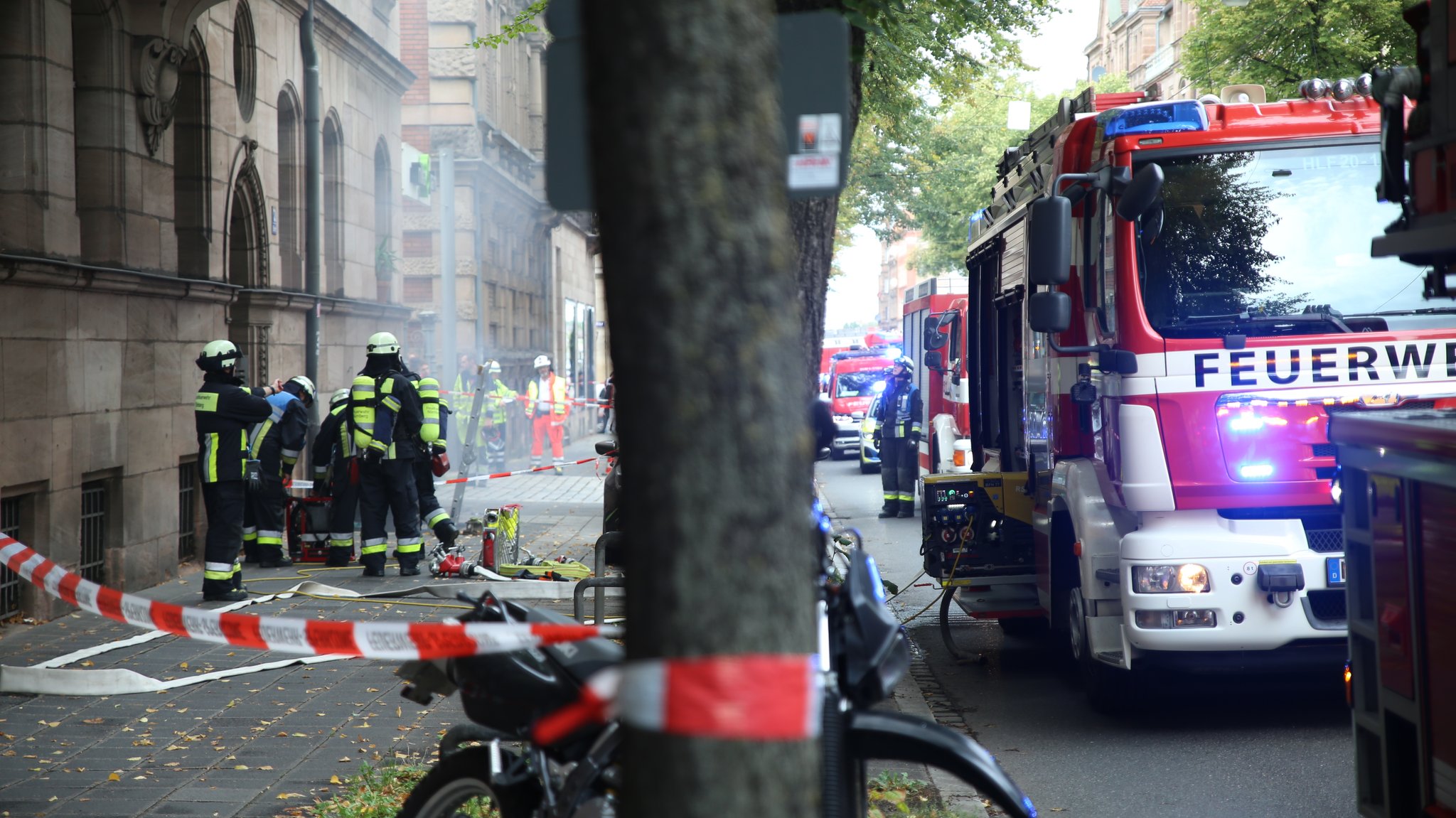Feuerwehrleute stehen in der Bucherstraße um einen Kellereingang versammelt, aus dem es raucht. | Bild: BR / Isabel Pogner Feuerwehrleute stehen in der Bucherstraße um einen Kellereingang versammelt, aus dem es raucht.
