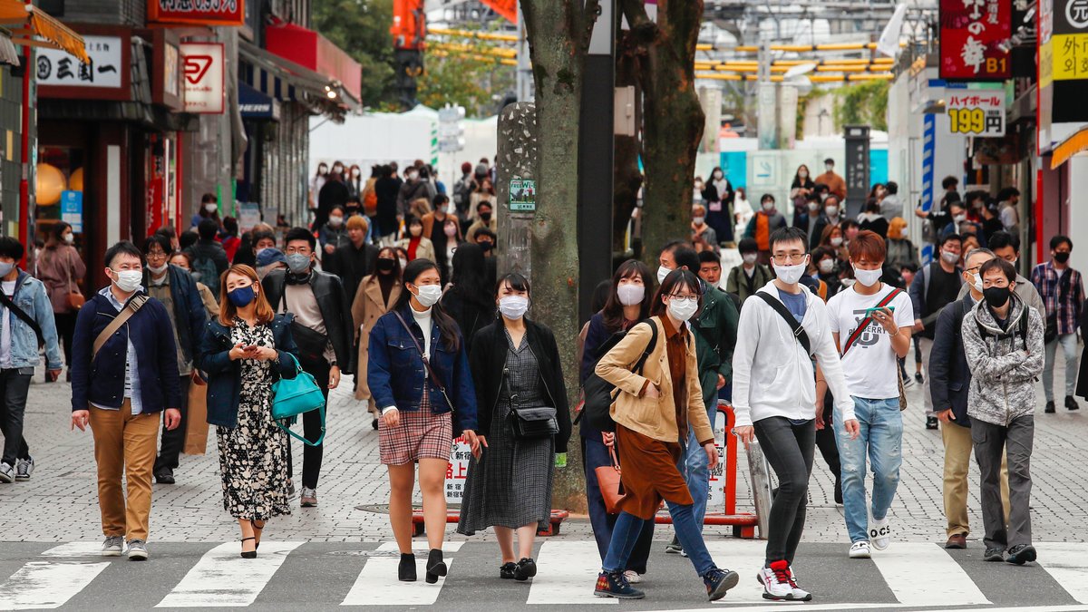 Maskentragende Menschen auf einer belebten Straße in Tokyo.