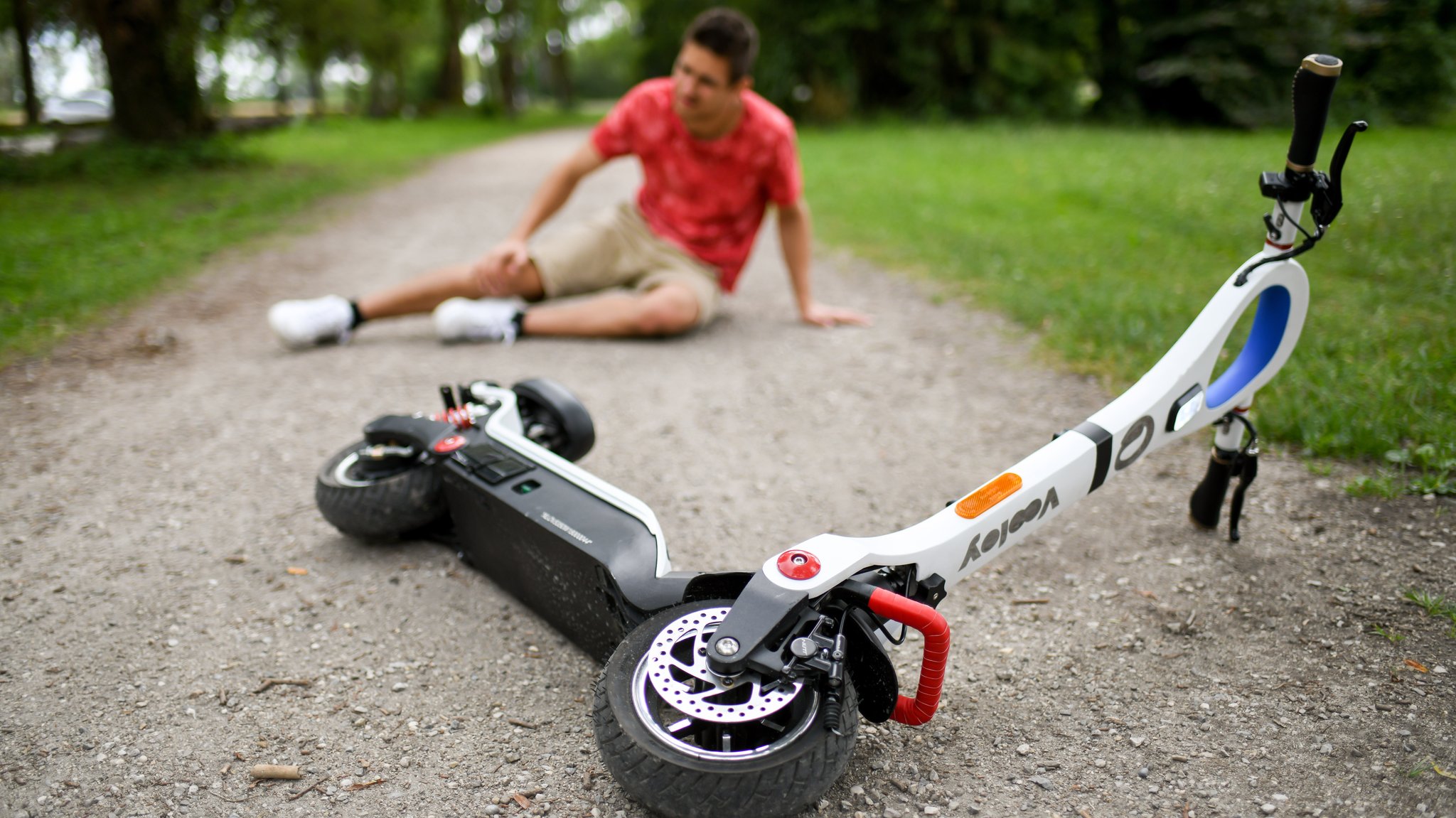 Symbolbild: Gestürzter E-Scooter-Fahrer fasst sich ans schmerzende Knie