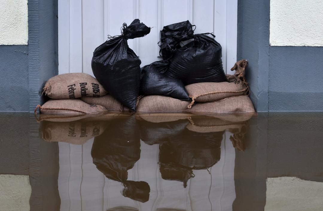 Sandsäcke liegen vor der Tür eines überschwemmten Hauses. 