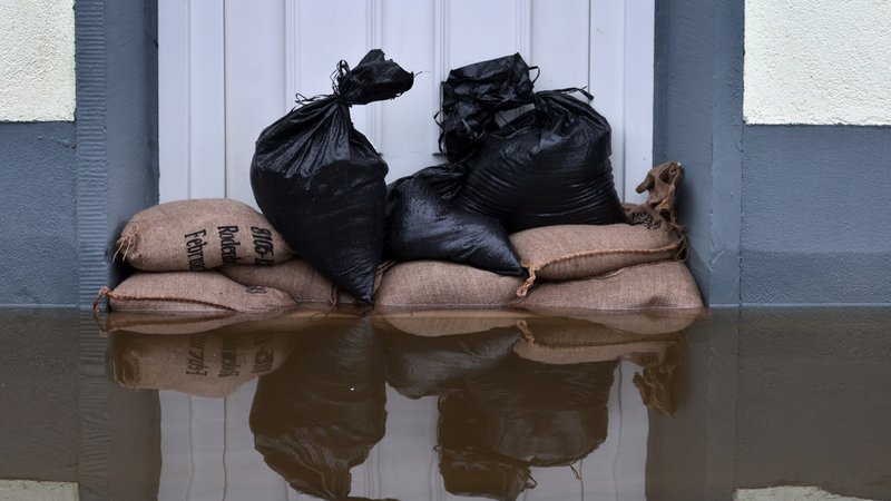 Sandsäcke liegen vor der Tür eines überschwemmten Hauses. 