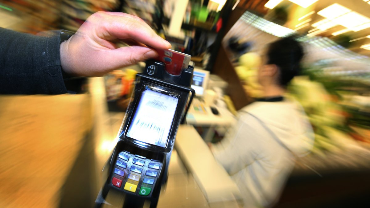 Eine EC-Karte wird in den Bezahl-Terminal an der Kasse eines Supermarktes geschoben. 