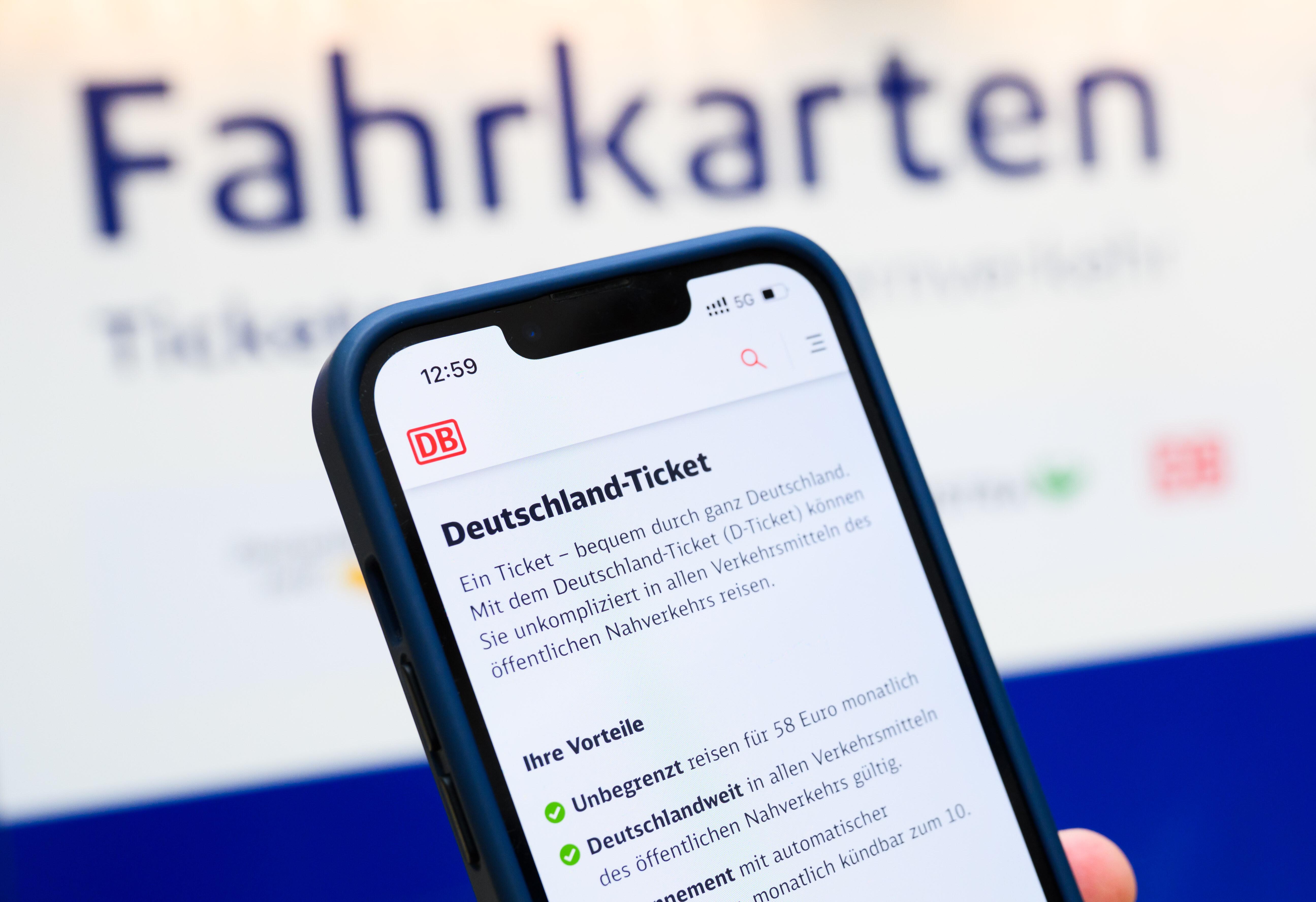 (Symbolbild) Eine Person hält ein Smartphone in der Hand, auf dessen Display eine Information zum Kauf des Deutschlandtickets zu sehen ist.