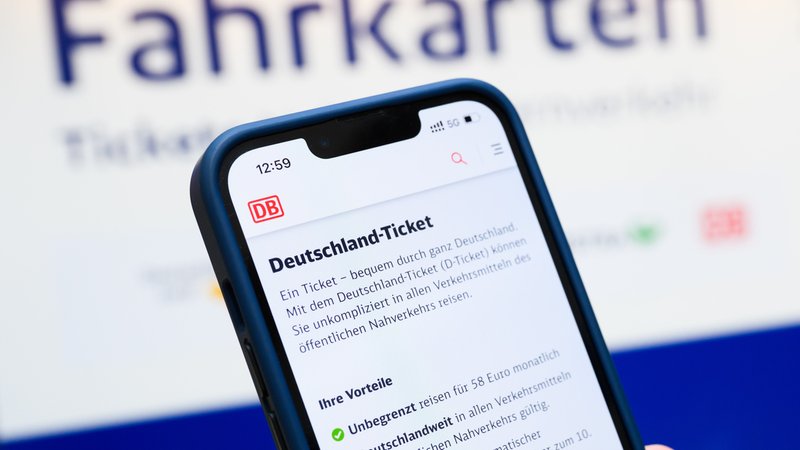 (Symbolbild) Eine Person hält ein Smartphone in der Hand, auf dessen Display eine Information zum Kauf des Deutschlandtickets zu sehen ist. | Bild: picture alliance/dpa | Julian Stratenschulte (Symbolbild) Eine Person hält ein Smartphone in der Hand, auf dessen Display eine Information zum Kauf des Deutschlandtickets zu sehen ist.
