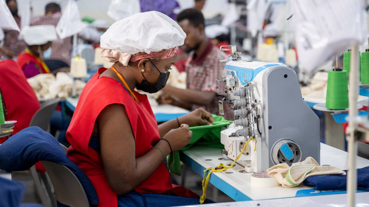 Eine Textilarbeiterin sitzt an einer Nähmaschine.