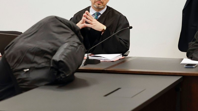 Der Angeklagte versteckt sich im Gericht hinter seiner Jacke. | Bild: picture alliance/dpa | Daniel Löb Der Angeklagte versteckt sich im Gericht hinter seiner Jacke.