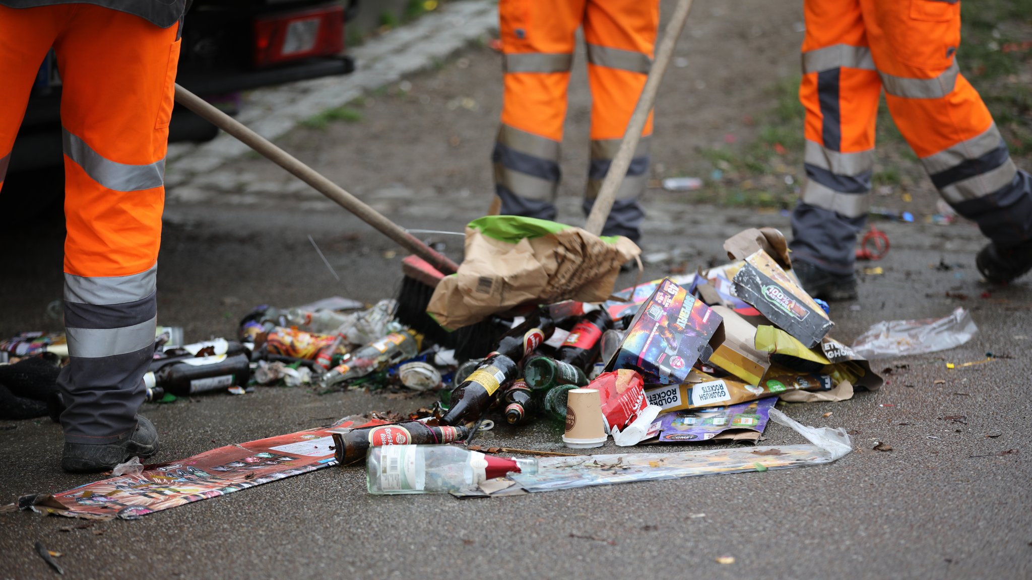 Symbolbild: Mitarbeitende einer Straßenreinigung kehren Silvestermüll zusammen.