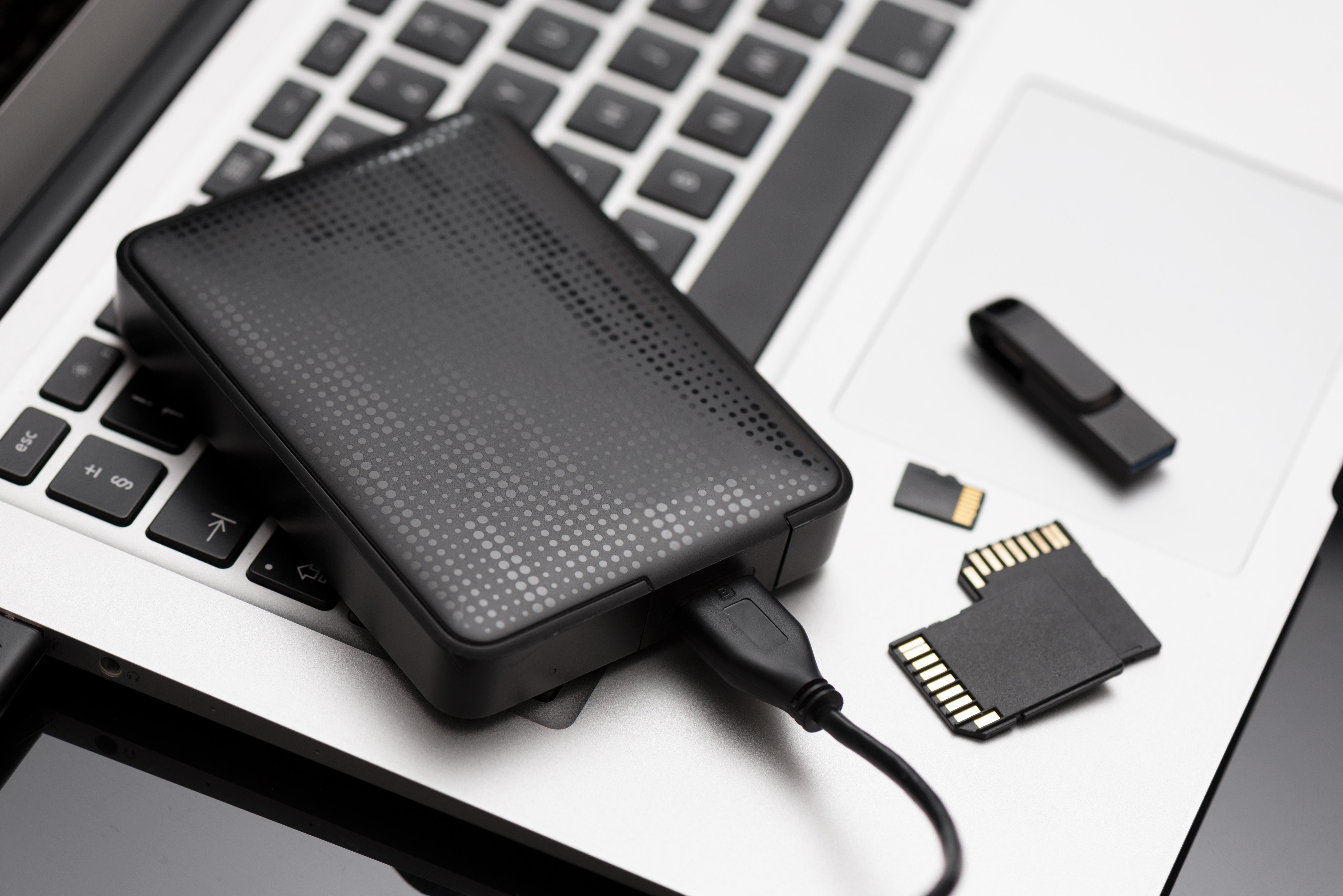 Eine externe Festplatte, zwei SD-Karten, eine Micro-SD-Karte und ein USB-Stick liegen auf einem Notebook (Symbolbild) 