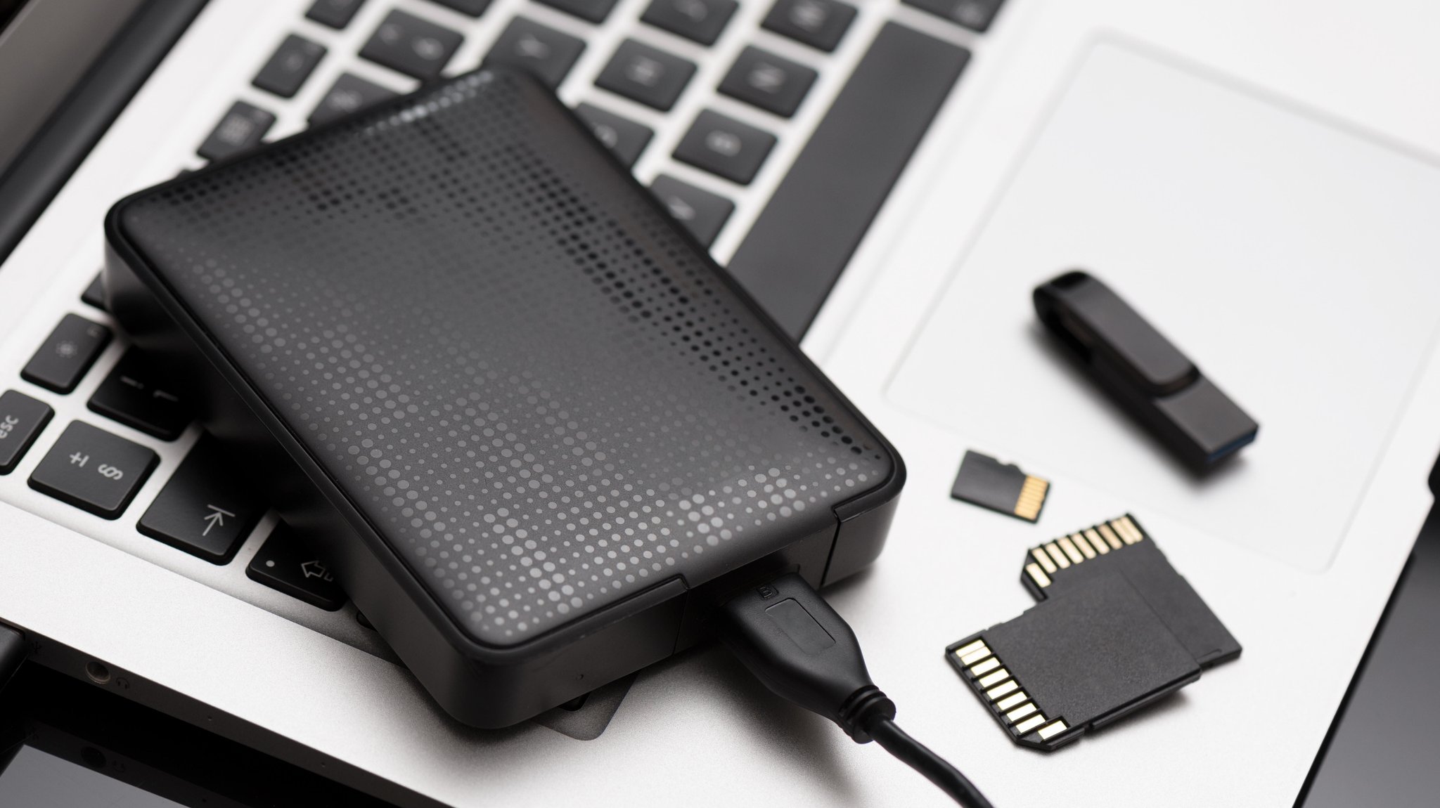 Eine externe Festplatte, zwei SD-Karten, eine Micro-SD-Karte und ein USB-Stick liegen auf einem Notebook (Symbolbild) 