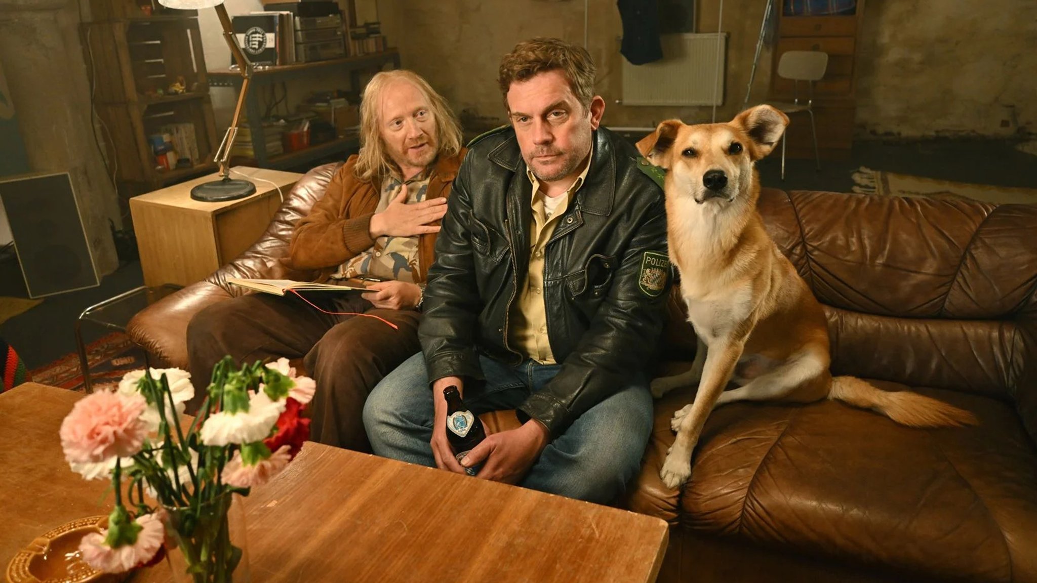 Mit Hund auf der Couch im Keller: Franz Eberhofer (Sebastian Bezzel) und Rudi Birkenberger (Simon Schwarz) in "Steckerlfischfiasko" | Bild: Bernd Schuller / Constantin Mit Hund auf der Couch im Keller: Franz Eberhofer (Sebastian Bezzel) und Rudi Birkenberger (Simon Schwarz) in "Steckerlfischfiasko"