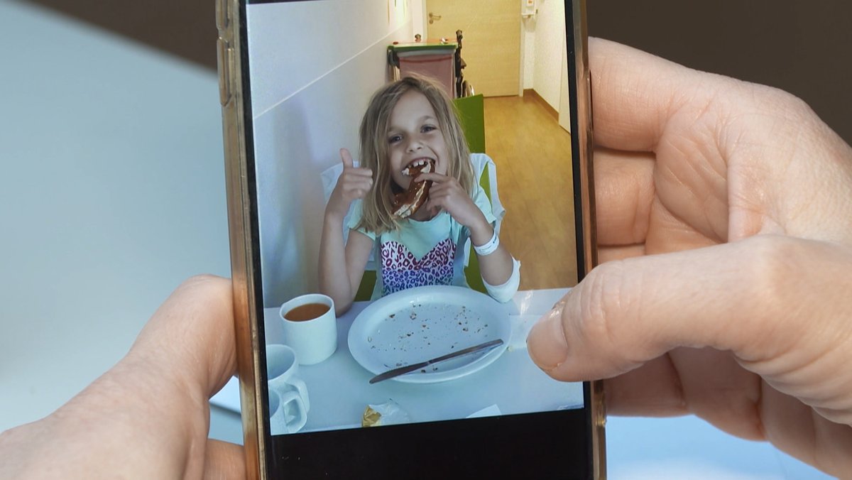 Ein Handybild eines Mädchens mit einer Breze am Frühstückstisch