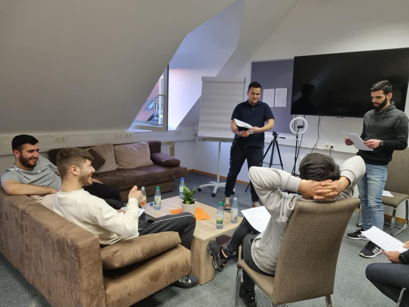 Junge Männer sitzen in einer Gruppenstunde in einem Seminarraum zusammen.