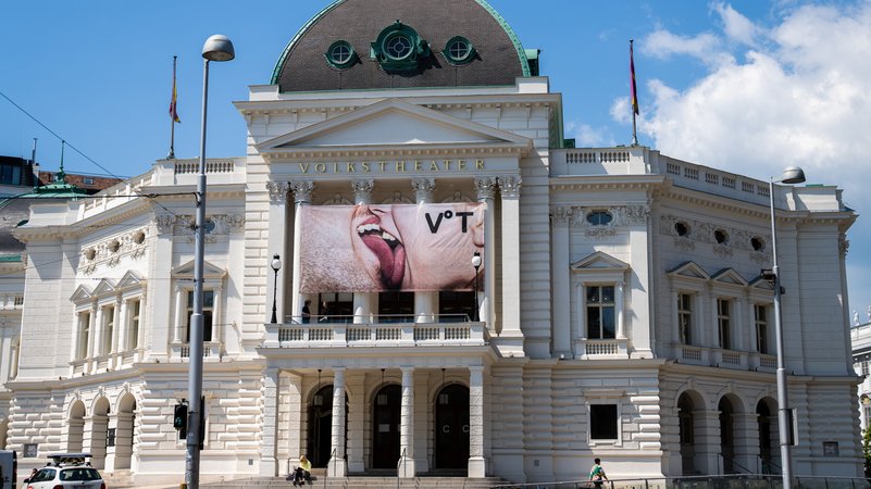 Bild des Wiener Volkstheaters, ein imposanter klassizistischer Bau, über dem Eingang hängt ein Transparent auf dem sich ein Mann und eine Frau leidenschaftlich küssen | Bild: picture alliance / GEORG HOCHMUTH / APA / picturedesk.com | GEORG HOCHMUTH Bild des Wiener Volkstheaters, ein imposanter klassizistischer Bau, über dem Eingang hängt ein Transparent auf dem sich ein Mann und eine Frau leidenschaftlich küssen