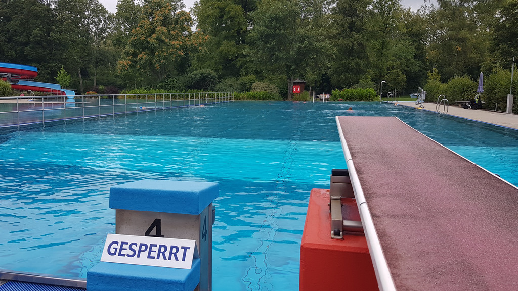 Blick auf ein Schwimmbecken vom Ein-Meter-Brett aus, vor dem ein Schilde mit der Aufschrift "Gesperrt" steht.