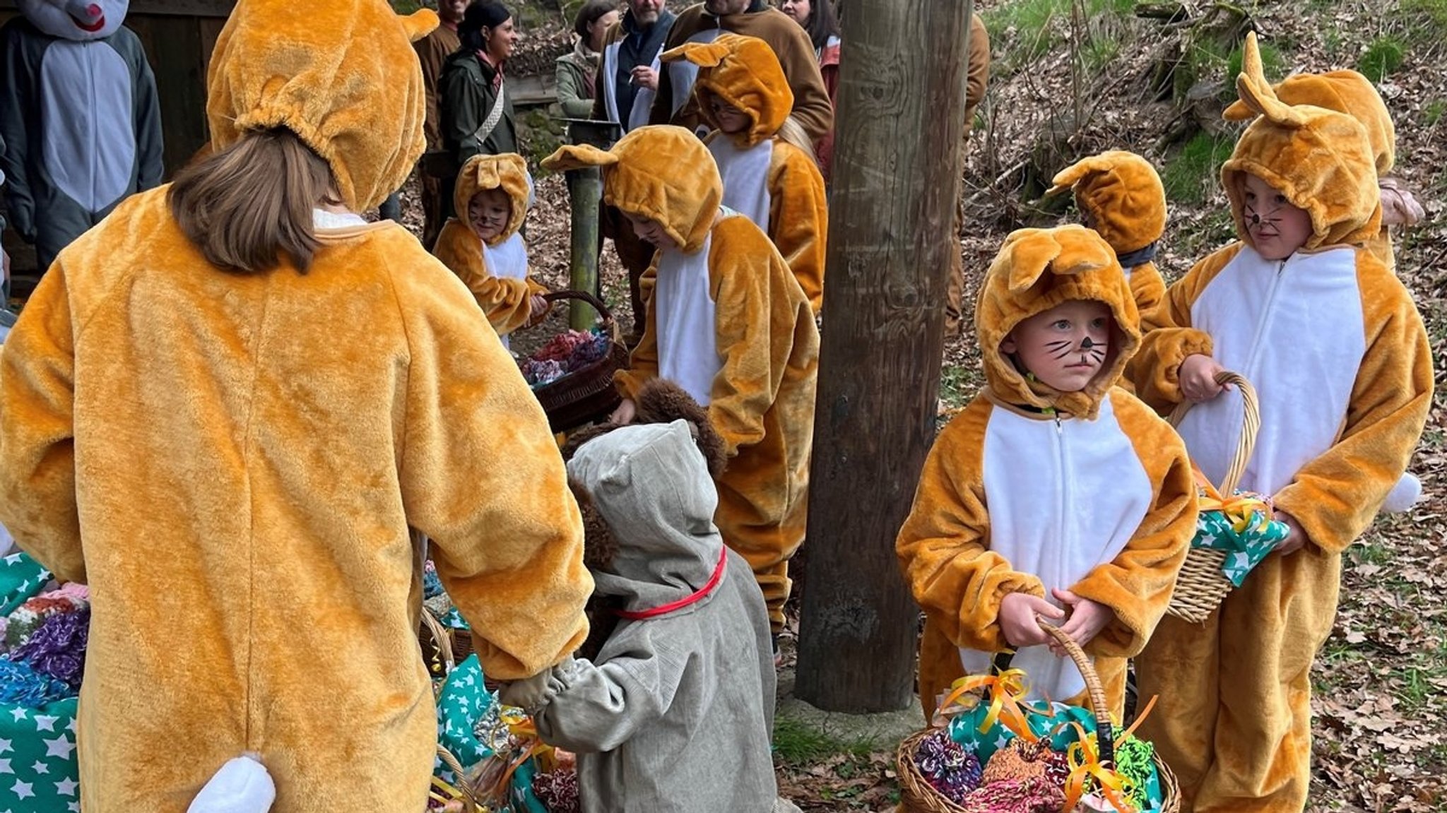 Kinder in Osterhasenkostümen mit Körben voller Eier und Geschenke. 