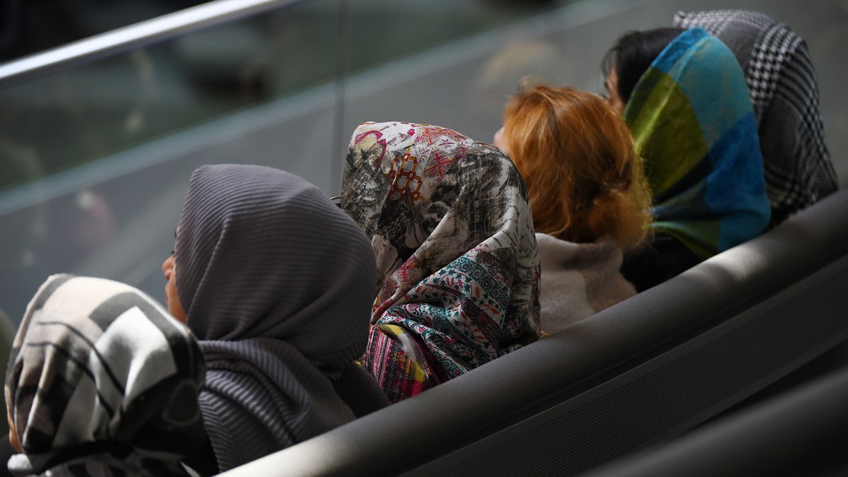 Junge Frauen mit verschiedenfarbigen Kopftüchern sitzen als Zuschauerinnen im Bundestag.