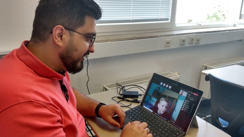 Mehmet Yilmaz vom Global Elternverein vor einem Laptop bei einer Teamskonferenz.