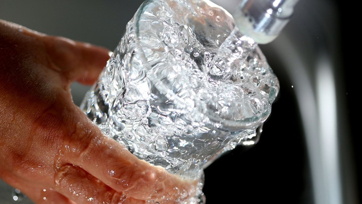 Wasser aus der Leitung läuft in ein Trinkglas
