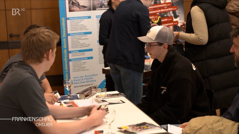 Interessierter bei Jobmesse informiert sich an Stand. | Bild: BR Interessierter bei Jobmesse informiert sich an Stand.