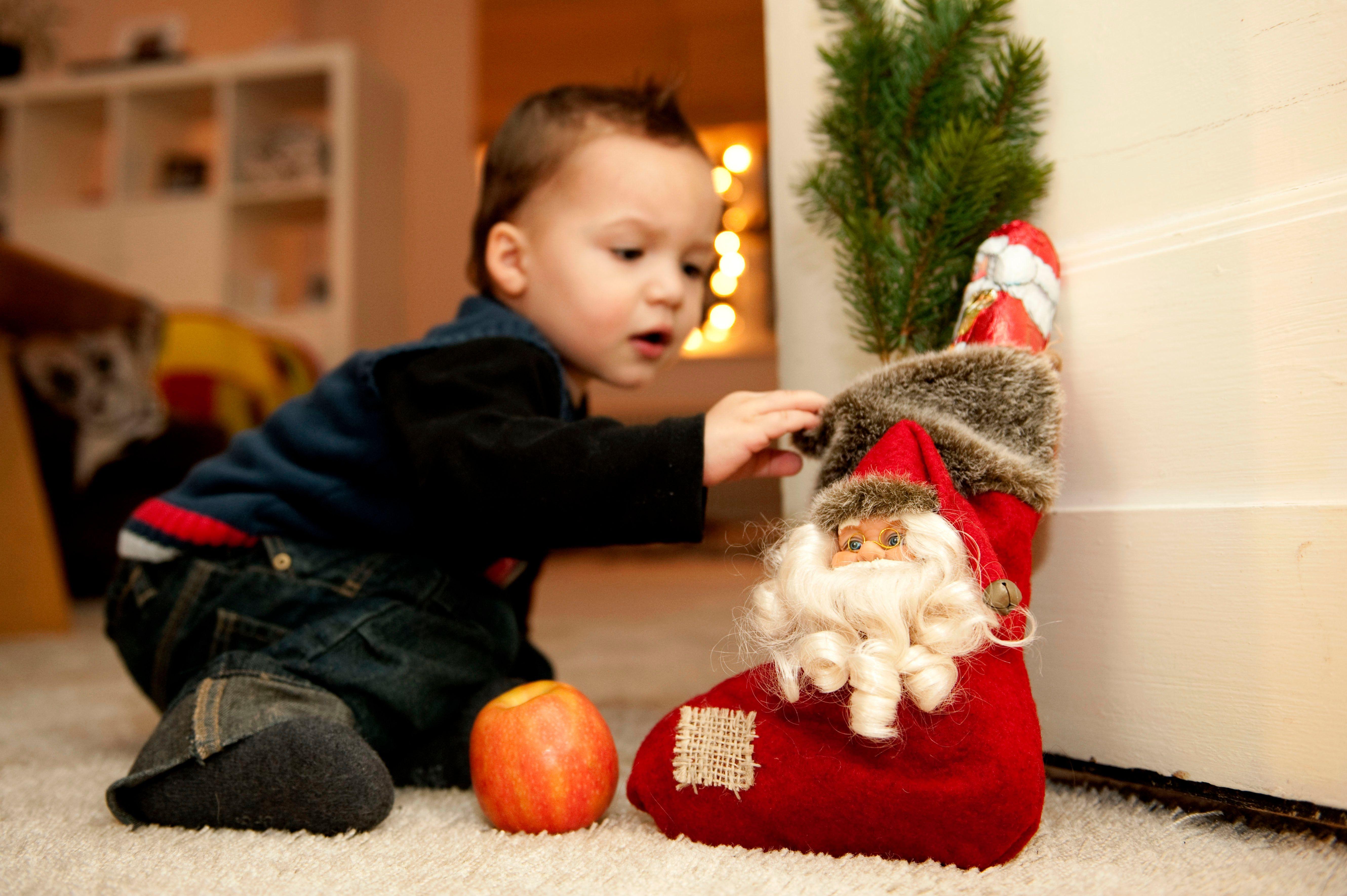 Kleinkind greift zu einem Stoffstiefel mit Nikolaus drauf und Schokonikolaus im Stiefel.