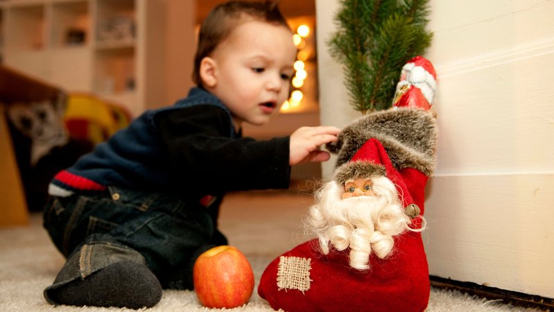 Kleinkind greift zu einem Stoffstiefel mit Nikolaus drauf und Schokonikolaus im Stiefel. | Bild: picture alliance / dpa | Robert Schlesinger Kleinkind greift zu einem Stoffstiefel mit Nikolaus drauf und Schokonikolaus im Stiefel.