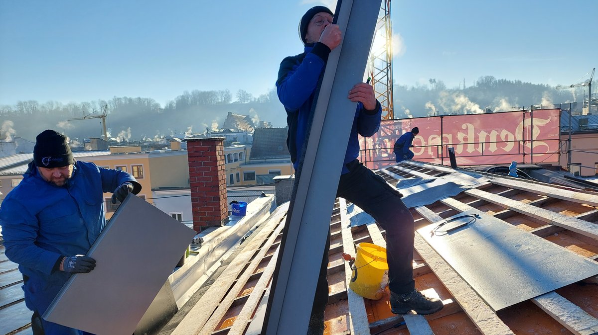 Mitarbeiter der Spenglerfirma Goepfert bei der Montage von Solarblechen auf dem Dach eines Hauses in der Altstadt von Wasserburg am Inn.
