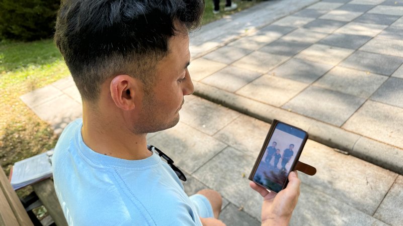 Der 29-jährige Hafiz aus Afghanistan sitzt auf einer Bank und video-telefoniert mit seiner Familie. | Bild: Katrin Bohlmann/BR Der 29-jährige Hafiz aus Afghanistan sitzt auf einer Bank und video-telefoniert mit seiner Familie.