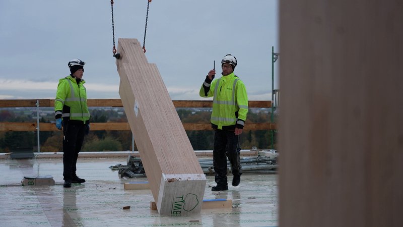 Zwei Bauarbeiter stellen eine Holzstütze auf