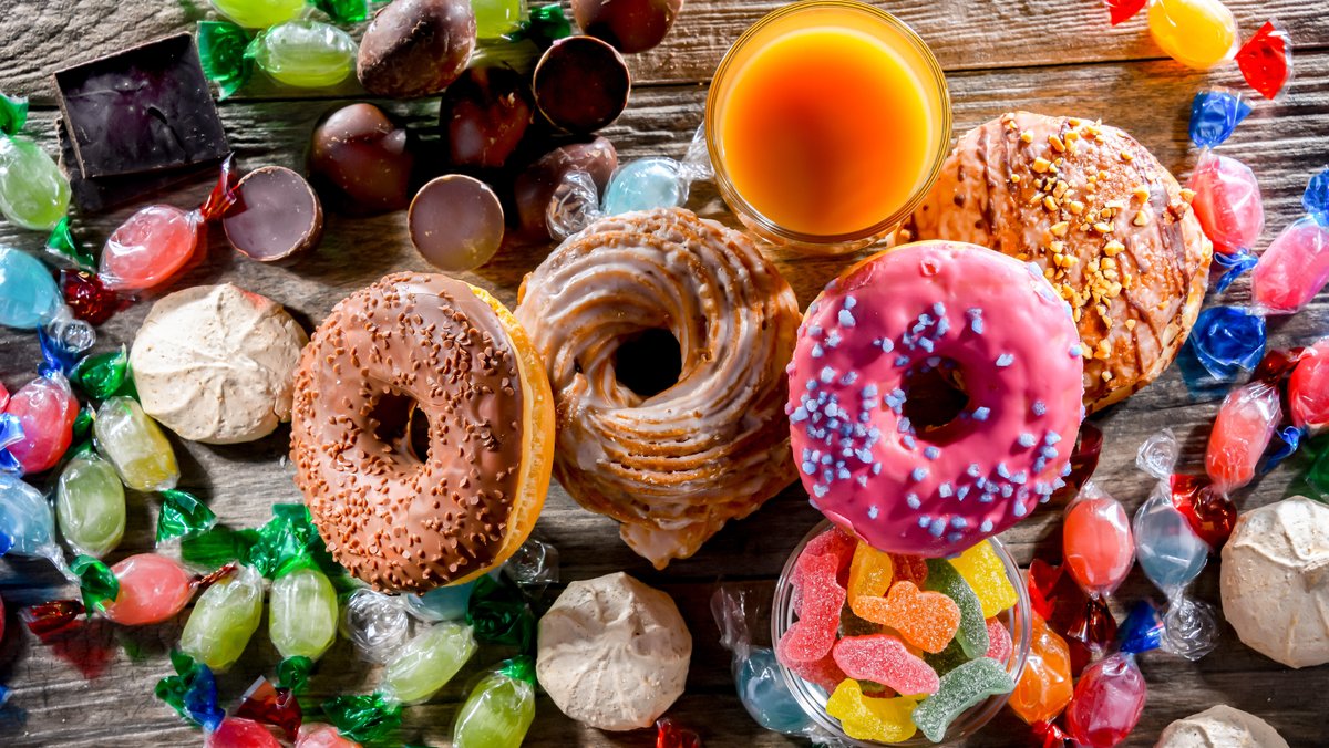 Süßigkeiten wie Bonbons, Schokolade, Gummibärchen und Donuts liegen durcheinander auf einem Tisch (Symbolbild)