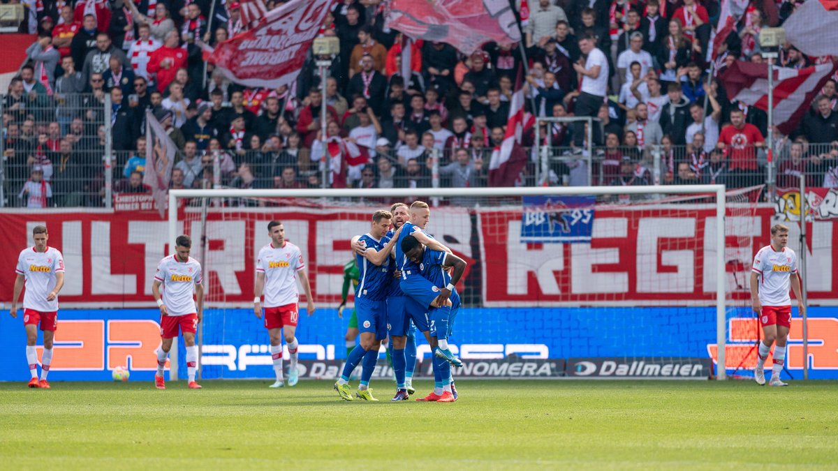 Die Rostocker Spieler bejubeln mit Kai Prögers Tor zum 0:1 nach sieben Spielminuten. Die Regensburger sind dementsprechend enttäuscht. 