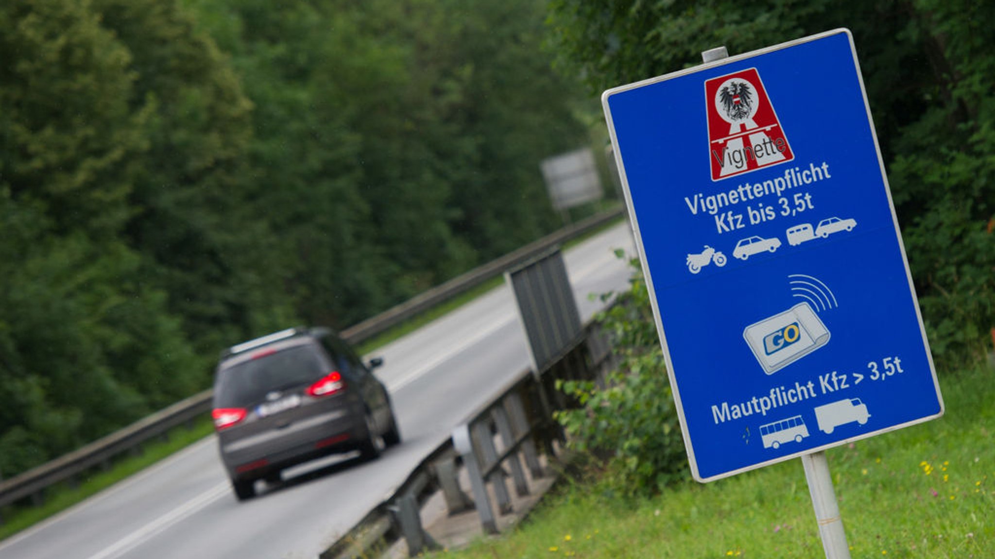 Ein Auto fährt in Kufstein (Österreich) auf der Zubringerstraße zur Autobahn an einem Hinweisschild zur Vignettenpflicht vorbei (Archivbild).