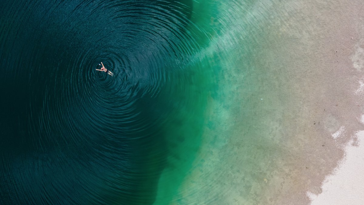Ein Mann genießt das schöne Wetter und schwimmt im Langwieder See. (Luftaufnahme mit einer Drohne)