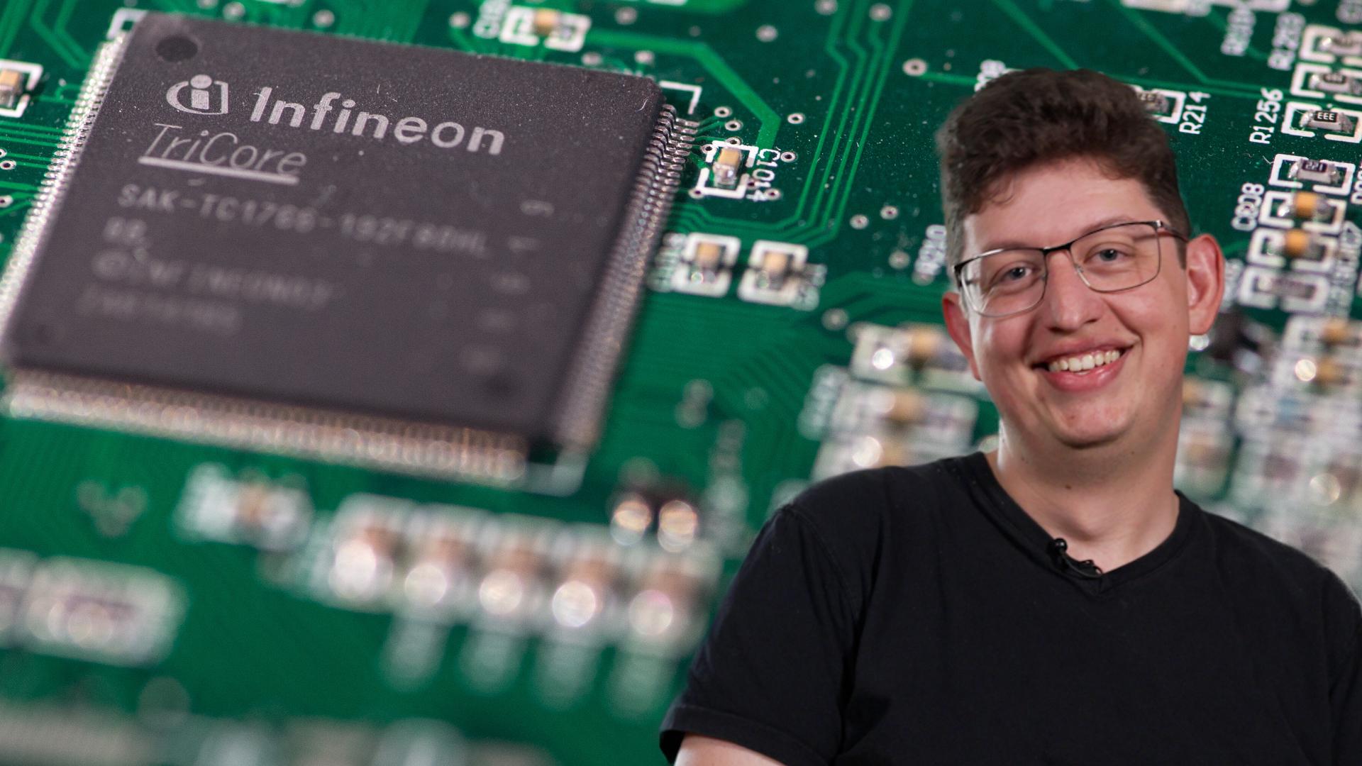 Korbinian im Porträt: Im Hintergrund ein 32bit-Prozessor von Infineon auf einem Referenz-Board für das Steuergerät eines Autos
