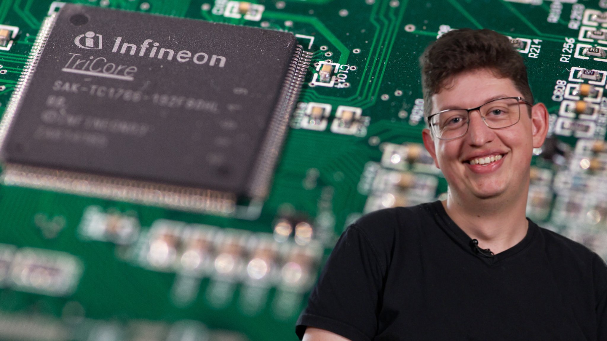Korbinian im Porträt: Im Hintergrund ein 32bit-Prozessor von Infineon auf einem Referenz-Board für das Steuergerät eines Autos